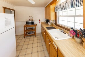 Cocina compacta con microondas, tostadora, lavamanos y armarios de madera.