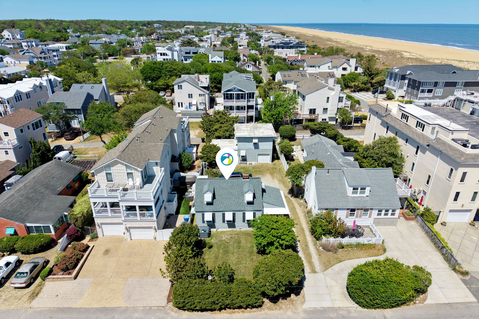 A residential area with houses, a beach, and a clear sky.
