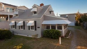 Ein zweistöckiges Haus mit Satteldach, überdachter Veranda und kleinem Anbau für eine Garage.