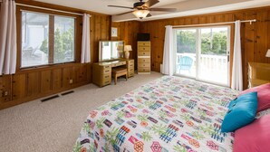 A bedroom with a bed, dresser, desk, and a large window. - Harshaw Beach House - North End Oceanfront (Virginia Beach)