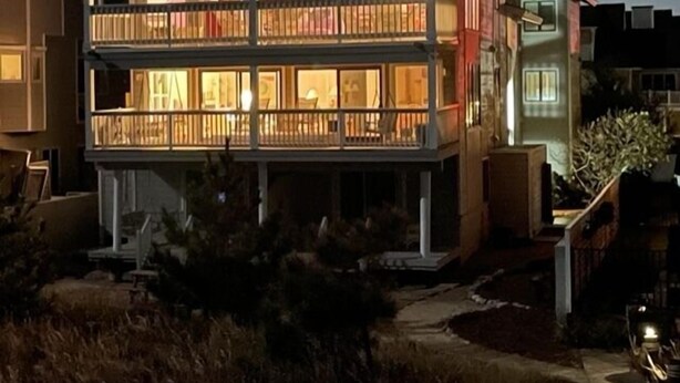 A two-story house with a balcony and a covered porch. - Dolphin's Den - Oceanfront - North End VB (Virginia Beach)