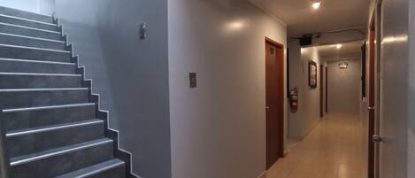 Um interior moderno com uma escada, um corredor e uma porta.