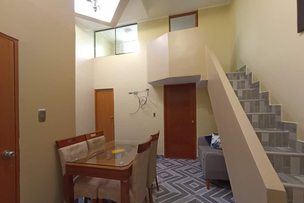 A compact living space with a dining area, a staircase, and a small seating area.