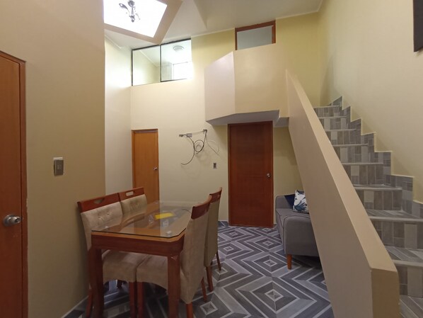 A compact living space with a dining area, a staircase, and a small seating area. - COLONIAL SUITE (Callao)