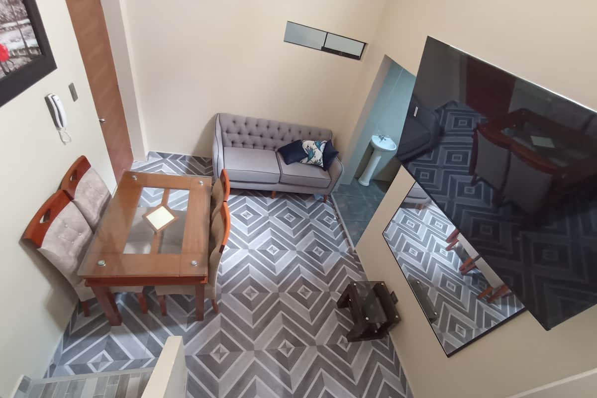 A living room with a sofa, a coffee table, and a TV mounted on the wall.