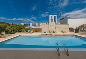A rooftop pool with lounge chairs and a view of a cityscape.