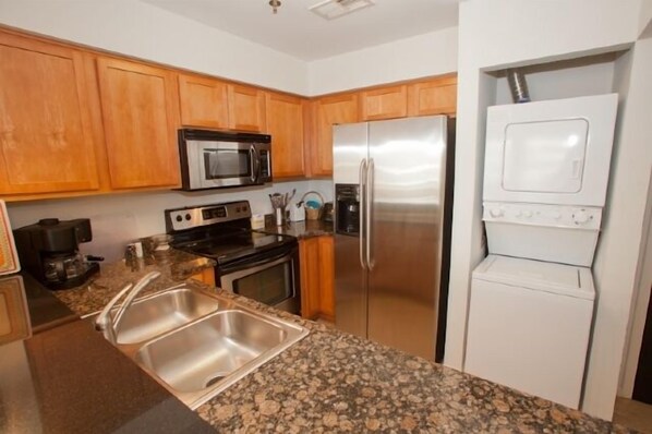 A kitchen with wooden cabinets, stainless steel appliances, granite countertops, and a built-in oven.