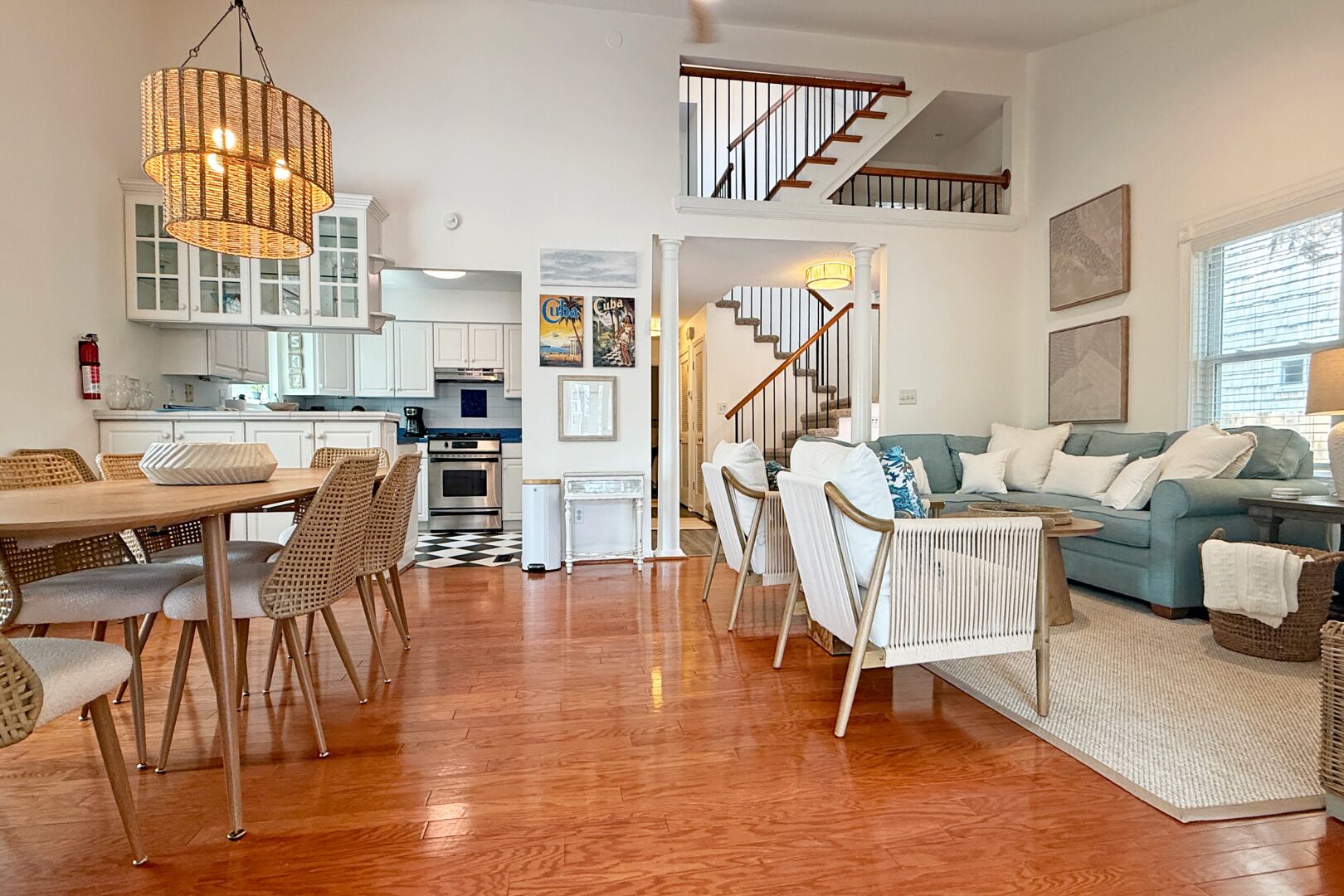 Uma sala ampla com uma mesa de jantar, cadeiras, um sofá e uma escada que leva a um andar superior.