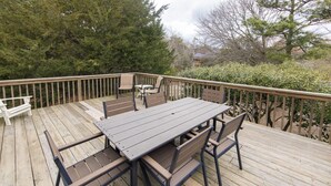 A wooden deck with a table and chairs, surrounded by trees and shrubs. - North End Paradise - North End VB (Virginia Beach)