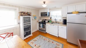 A kitchen with white cabinets, a microwave, an oven, a sink, and a refrigerator. - Conch Shell Cottage - North End VB (Virginia Beach)