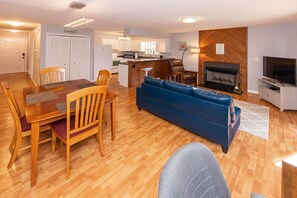 A modern living room with a wooden dining table, blue sofa, and a fireplace.