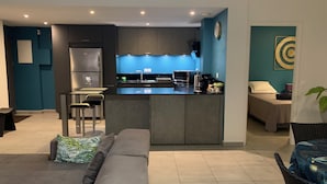 A modern kitchen with a central island, bar stools, and a refrigerator.