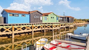 A wooden pier with colorful wooden buildings, boats docked at the end, and calm water reflecting the structures. - Gorgeous home in Saint-Martin-de-Ré with WiFi (Saint-Martin-de-Ré)