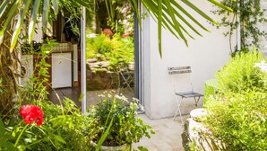 A small, enclosed garden area with a patio table and chairs, surrounded by lush greenery and flowering plants. - Gorgeous home in Saint-Martin-de-Ré with WiFi (Saint-Martin-de-Ré)