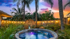 A hot tub surrounded by lush greenery and a wooden fence with string lights. - Stunning Retreat - Hot Tub - Sauna - Heated Pool - Games Room- Cold Plunge (Palm Beach Gardens)