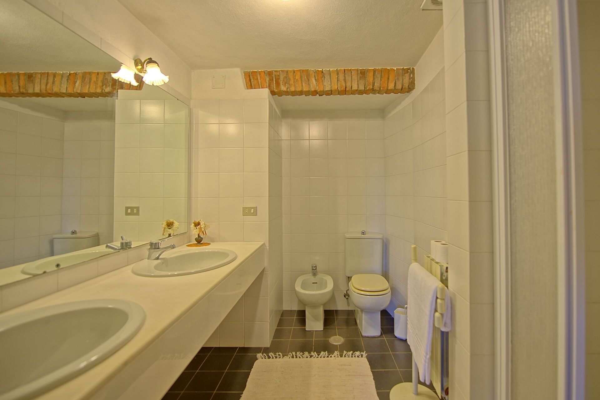 A bathroom with two sinks, a bidet, and a toilet.