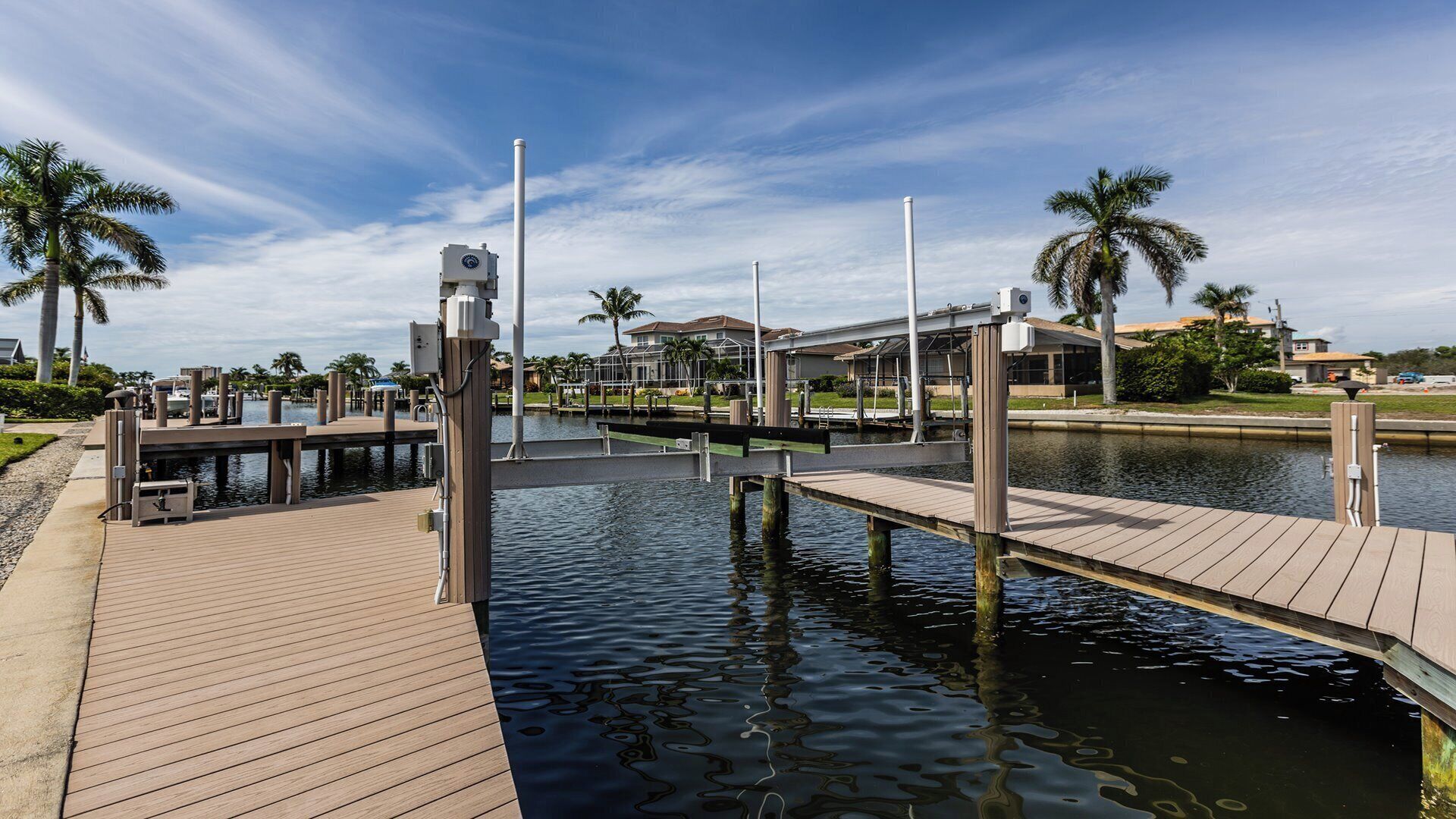 A waterfront dock area with wooden walkways, a marina, and residential buildings in the background.