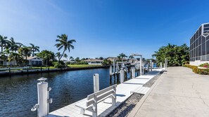 A waterfront property with a dock, a boat, and a modern building. - Stunning 4 bedroom home with 3 bathrooms, heated pool, and spa (Marco Island)