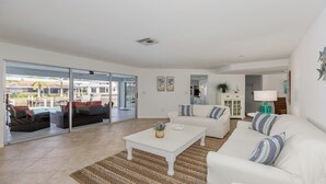 Un vaste espace de vie comprenant un canapé blanc, une table basse et une vue sur une piscine et un espace de détente extérieur.