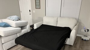 A compact living space with a sofa, a black bedspread, a small table, and a charging station. - Get Cozy in this newly renovated home by The Villages! (Lady Lake)
