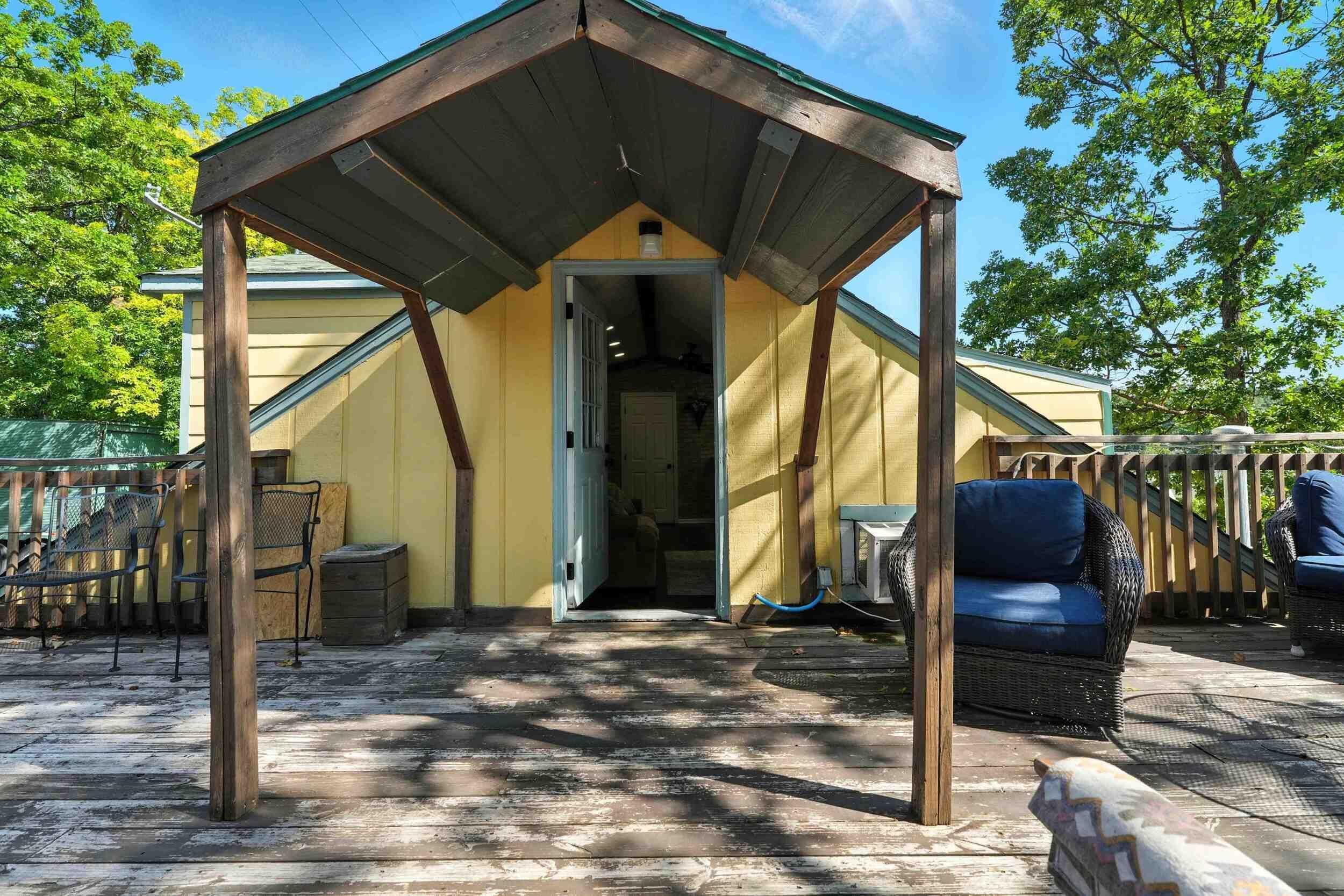 Un espace extérieur abrité, doté d’une structure en bois, d’une chaise en osier et d’une petite table.