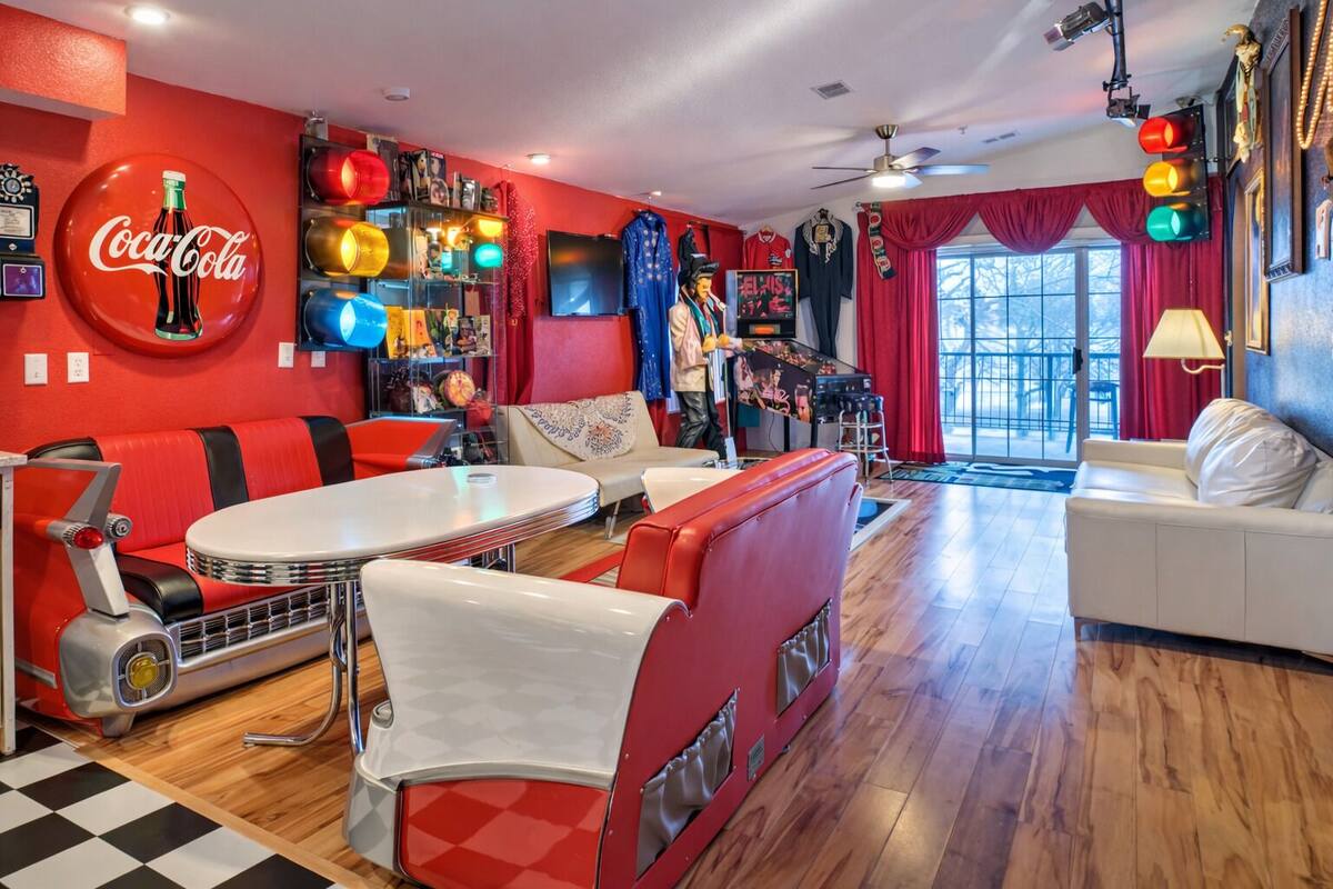 A retro-themed living room with a red and white color scheme, a vintage car, and a Coca-Cola sign.