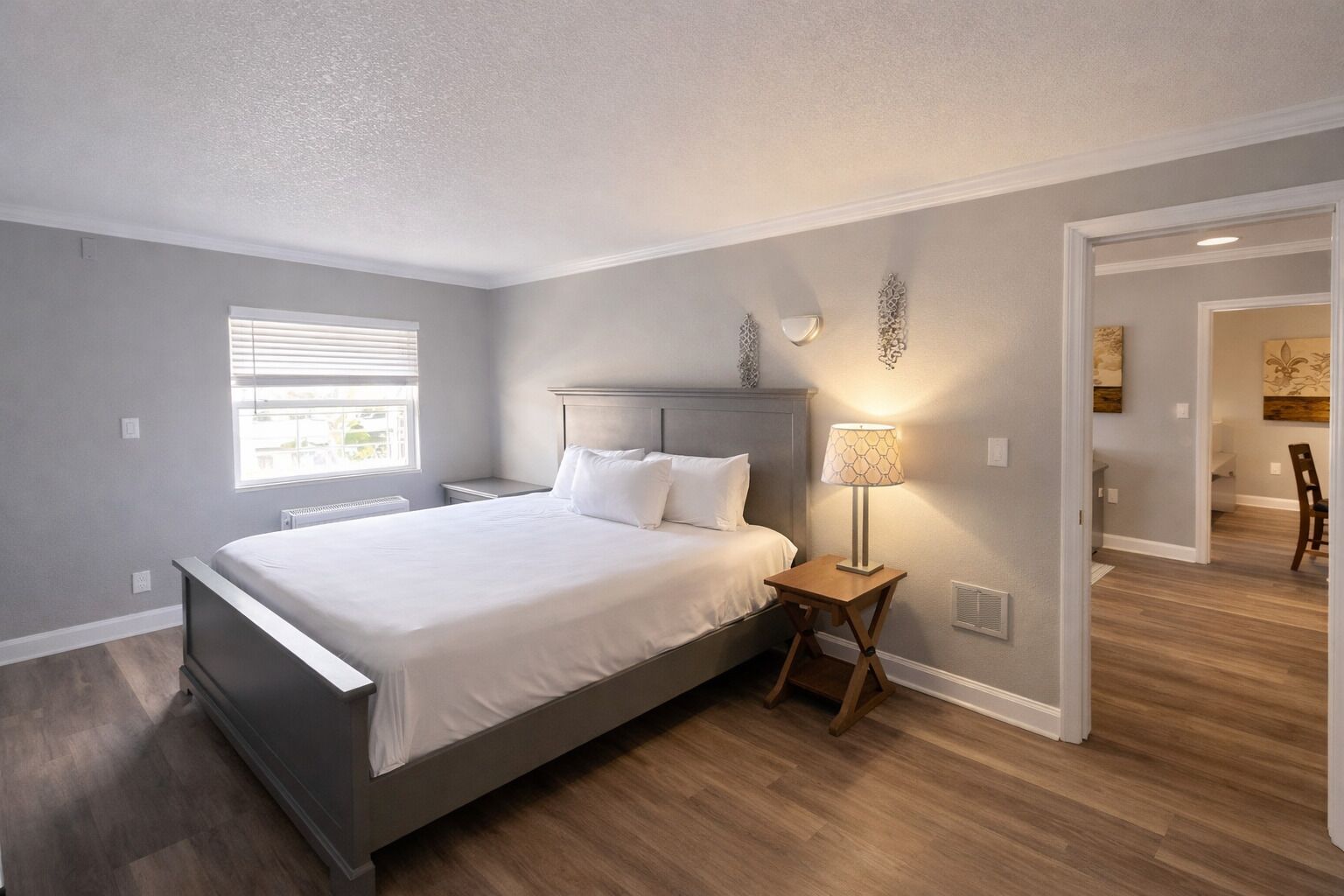 Une chambre à coucher moderne avec un lit, une table de chevet, une lampe et une fenêtre.