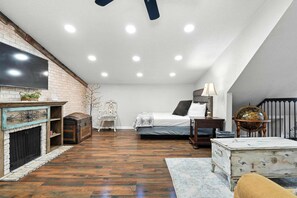 Une chambre à coucher avec un lit, une commode, une cheminée et un téléviseur.