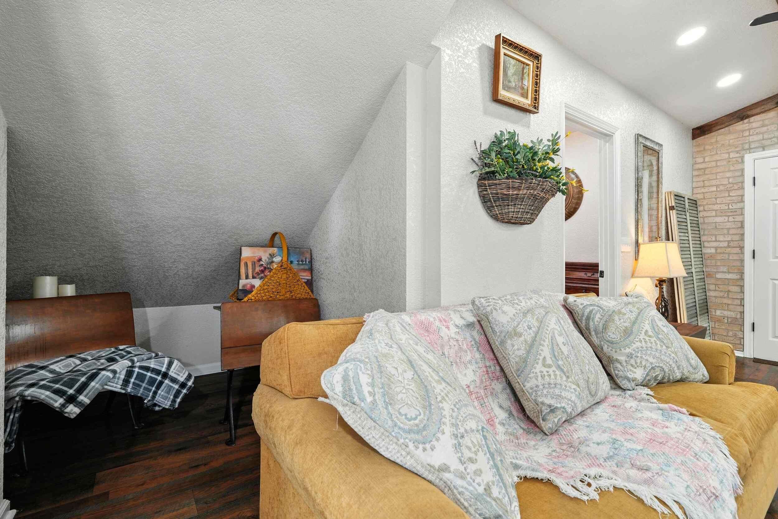 A living room with a sofa, a chair, a small table, and a wall-mounted plant.