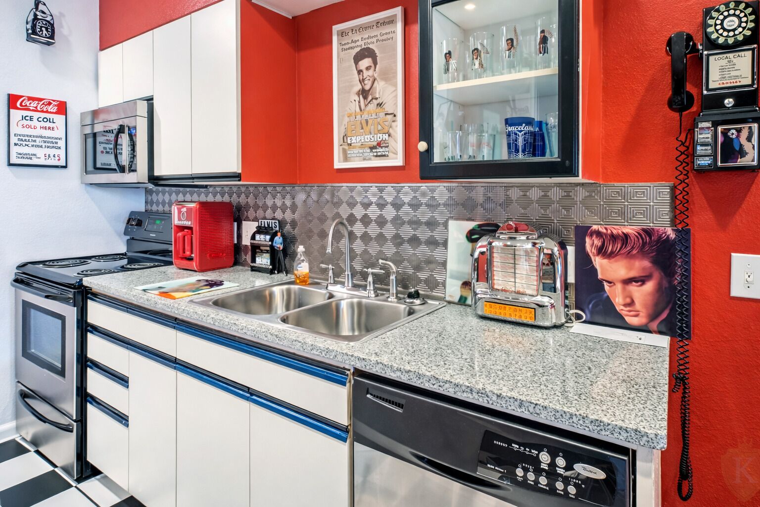 A kitchen with a red backsplash, stainless steel appliances, a coffee machine, and a vintage radio.