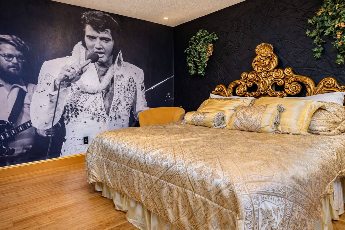 A bedroom with a large poster of a musician, a golden ornate headboard, and a patterned bedspread.