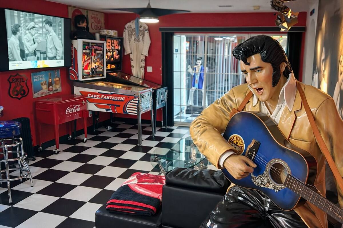 A room with a checkered floor, a Coca-Cola refrigerator, a jukebox, and a statue of a man playing a guitar.