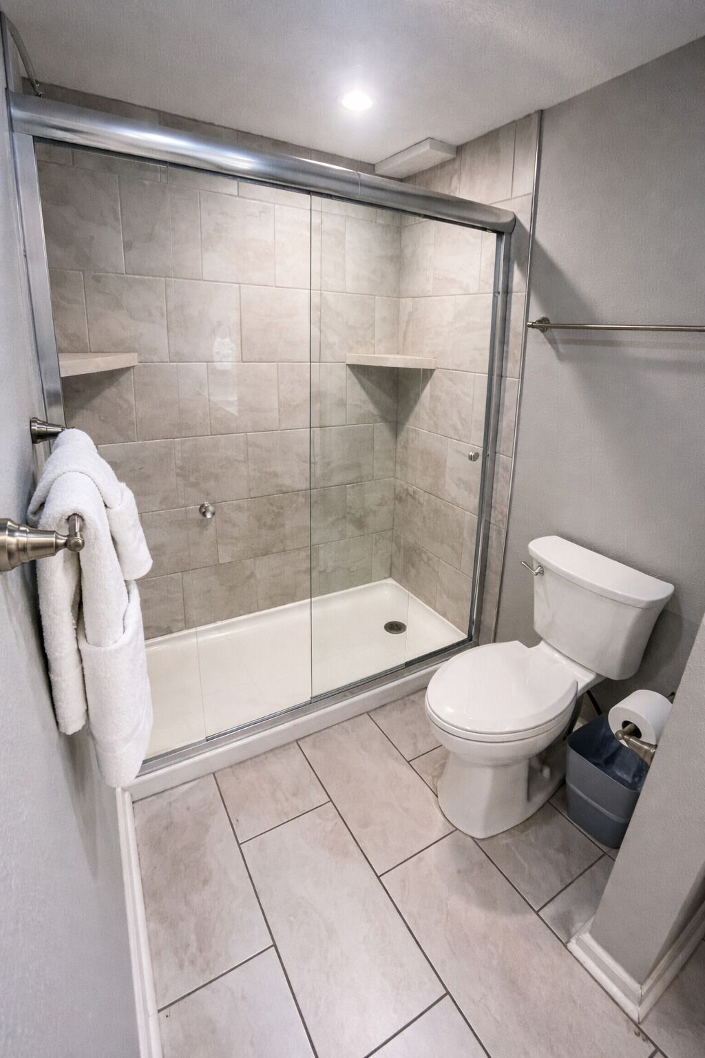 A bathroom with a glass-enclosed shower, a toilet, and a towel rack.