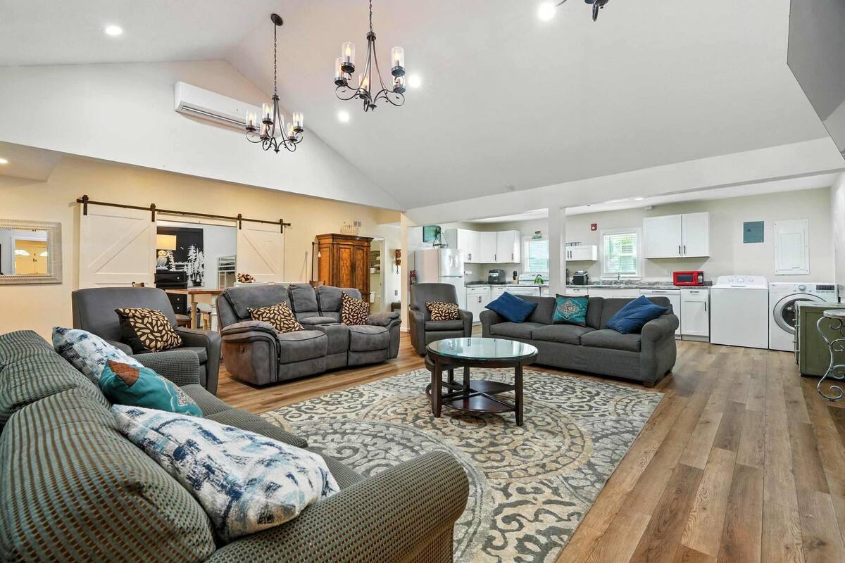 A spacious living room with sofas, a coffee table, and a chandelier.