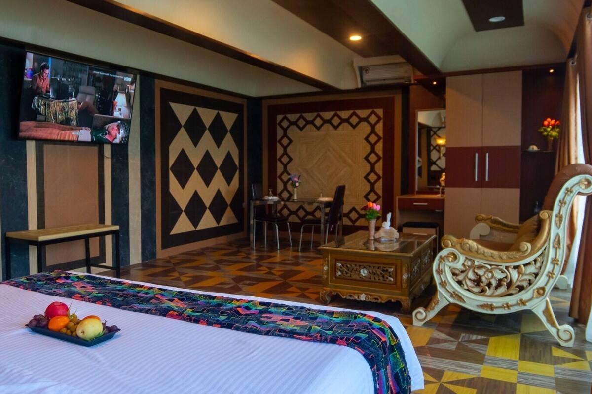 A hotel room with a bed, a TV, a desk, and a chair.