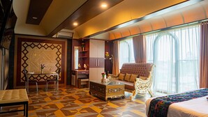 Una habitación de hotel con suelo estampado, un sofá, una cama, una mesa de comedor con sillas y un aparador decorativo.