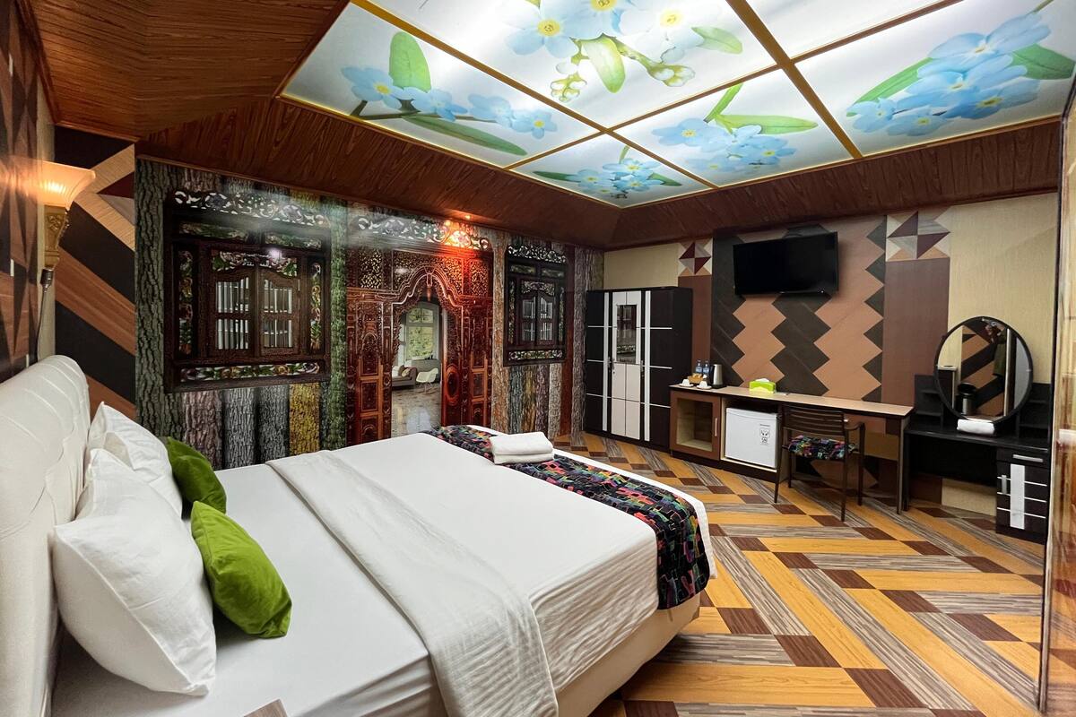A bedroom with a bed, a desk, a wardrobe, and a television.