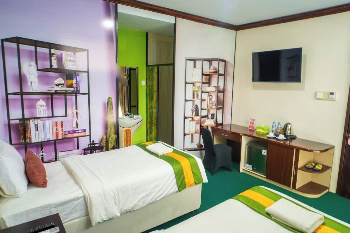 A hotel room with a bed, a desk, a TV, and a bookshelf.