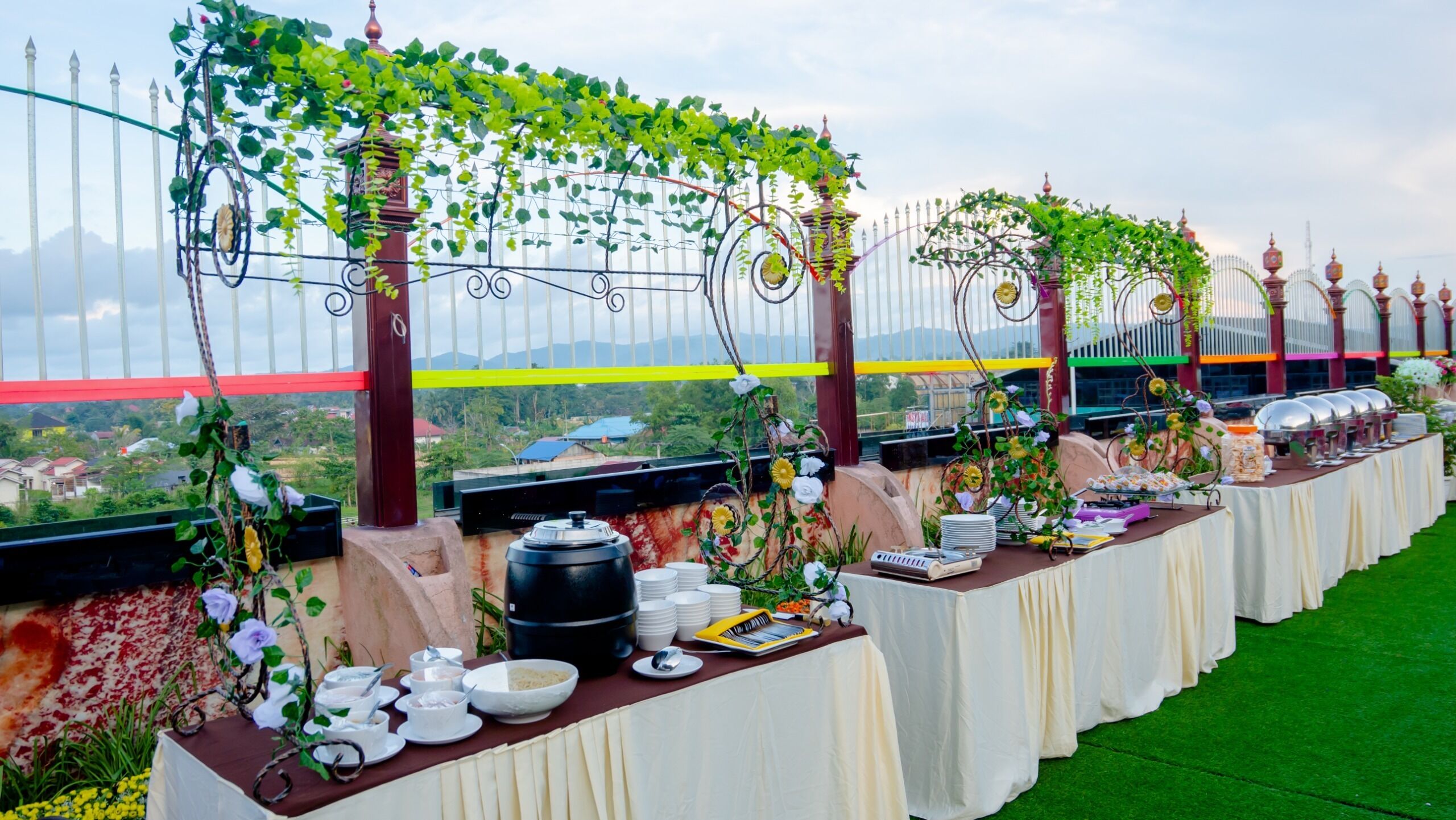 Un buffet disposé sur une longue table, avec différents récipients contenant de la nourriture et des plantes décoratives.