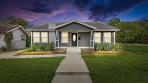 A two-story house with a front porch, a driveway, and a well-maintained lawn. - ADU Washer and Dryer Kitchen Walk Bishop Arts (Dallas)