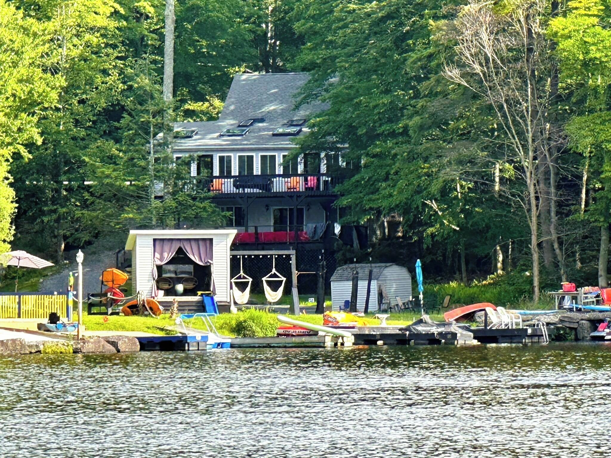 Un chalet au bord du lac, doté d’un quai, d’un petit bateau et d’un espace abrité avec des sièges d’extérieur.