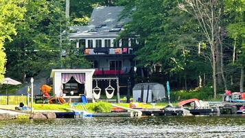 Un chalet au bord du lac, doté d’un quai, d’un petit bateau et d’un espace abrité avec des sièges d’extérieur.