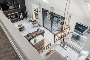 A modern living room with a fireplace, a dining area, and a game table.