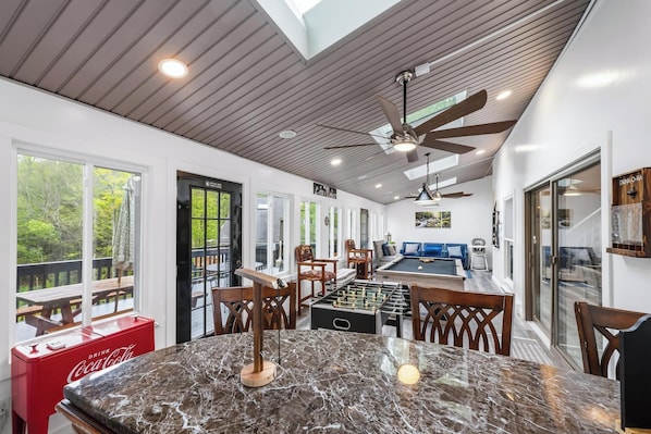A spacious room with a foosball table, a Coca-Cola cooler, and a pool table.