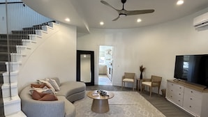 A modern living room with a grey sofa, a coffee table, and a TV on a cabinet. There is a staircase on the left and a door leading to another room. - Stay in the top 2 floors of the brand new Silo Inn, near Zion!  (Washington)