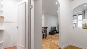 Un interior moderno con piso de madera en espiga, paredes blancas y una zona de comedor con televisor.