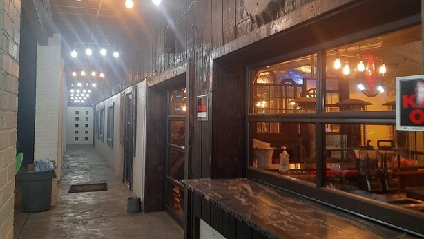 A narrow corridor with a bar area on the right, featuring a counter and hanging lights. - Black River Motel and Restaurant (Lesterville)