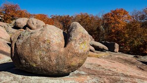 A large boulder in a natural setting with autumn-colored trees in the background. - Black River Motel and Restaurant (Lesterville)