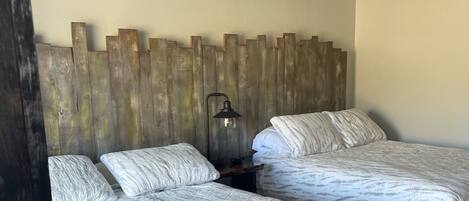Un dormitorio con dos camas, cabeceros de madera, un ventilador de techo y una mesita de noche con lámpara.
