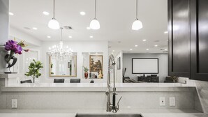 A modern kitchen with a central island, pendant lighting, and a large chandelier.